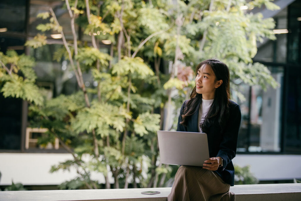 Young businesswoman sits with her laptop in a green modern office space | ANG