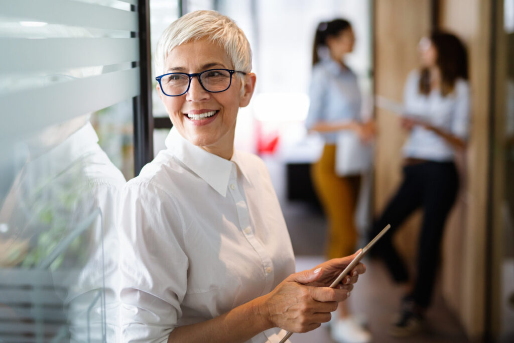 Confident stylish european mature business woman standing at workplace | ANG