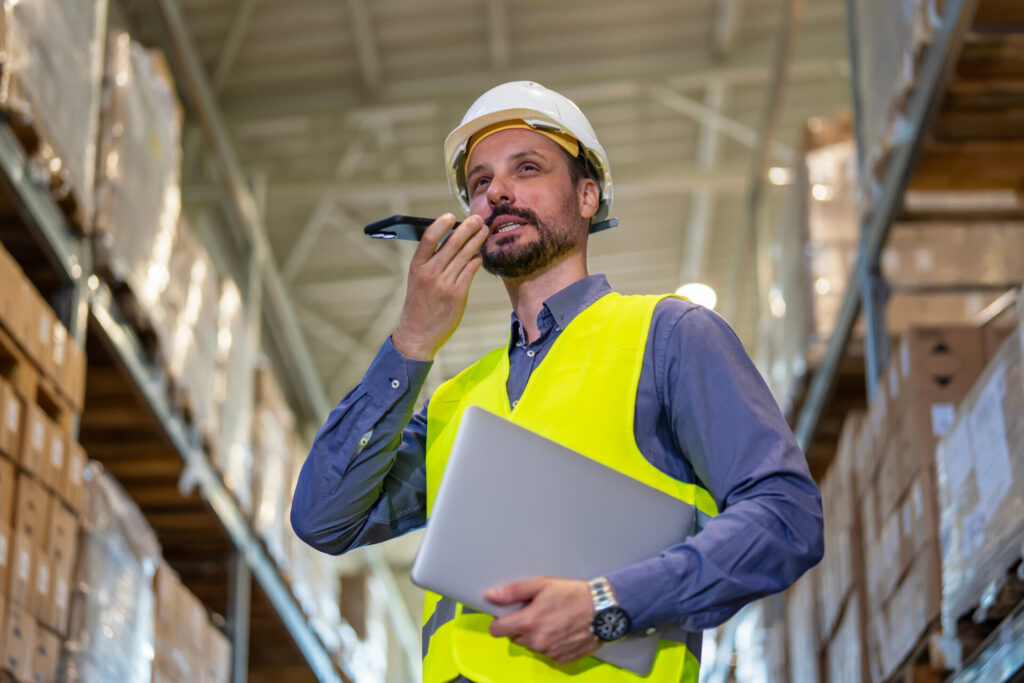 Warehouse worker talking on smartphone using voice command | ANG