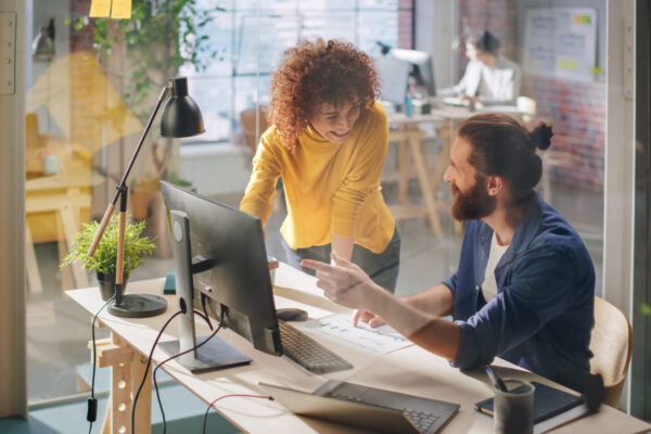Two Stylish Employees Discussing Work-Related Projects on Comput Two Stylish Employees Discussing Work-Related Projects on Comput