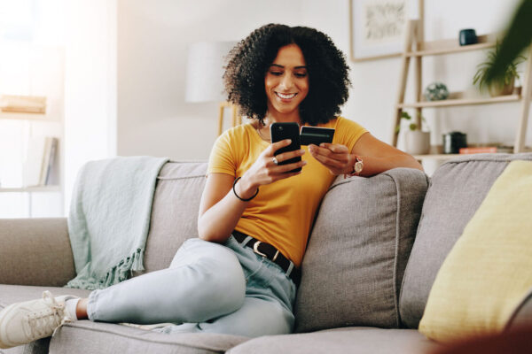 Credit-card,-happy-and-woman-on-sofa-with-phone-for-online-shopping,-web-store-sale-and-purchase. Credit-card,-happy-and-woman-on-sofa-with-phone-for-online-shopping,-web-store-sale-and-purchase.