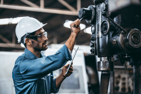 Engineer-working-at-industrial-machinery-in-factory.-Manual-workers-cooperating-while-measuring-a-electronic. Engineer-working-at-industrial-machinery-in-factory.-Manual-workers-cooperating-while-measuring-a-electronic.