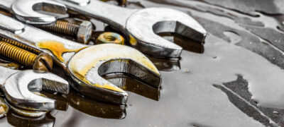 Metallic wrenches, nuts and bolts stained with motor oil (with space for text)