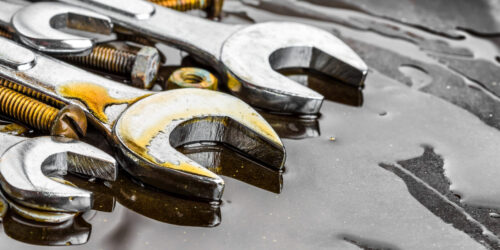 Metallic wrenches, nuts and bolts stained with motor oil (with space for text)