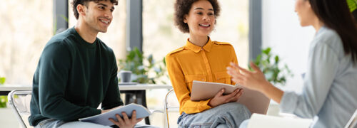College collaboration. Cheerful multiracial students talking and discussing their educational project together, sitting in classroom on chairs