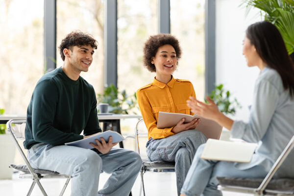 College collaboration. Cheerful multiracial students talking and discussing educational project together in classroom College collaboration. Cheerful multiracial students talking and discussing their educational project together, sitting in classroom on chairs