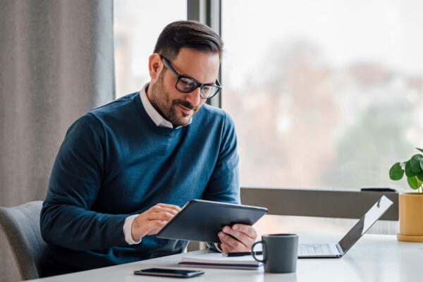 Young-businessman-using-digital-tablet-while-working-in-business-office. Young-businessman-using-digital-tablet-while-working-in-business-office.